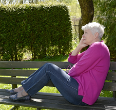 Ältere Frau sitzt auf einer Parkbank