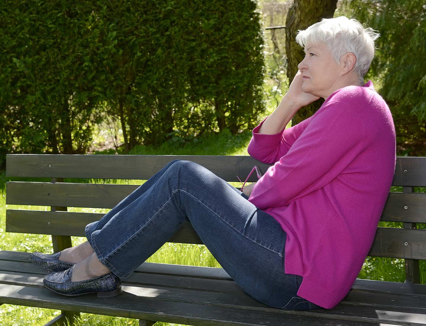 Ältere Frau sitzt auf einer Parkbank